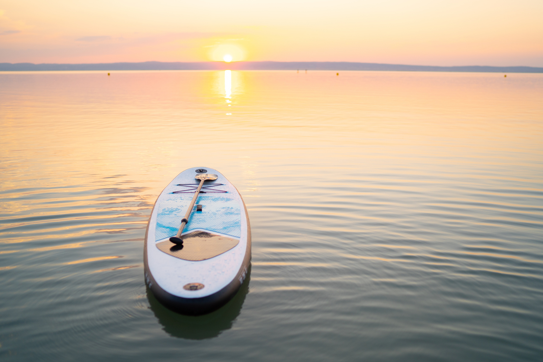 standup paddle board on empty lake in sunset